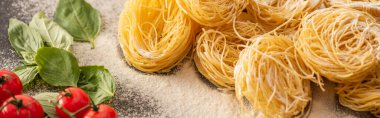 raw Italian Capellini with vegetables and flour on black background, panoramic shot clipart