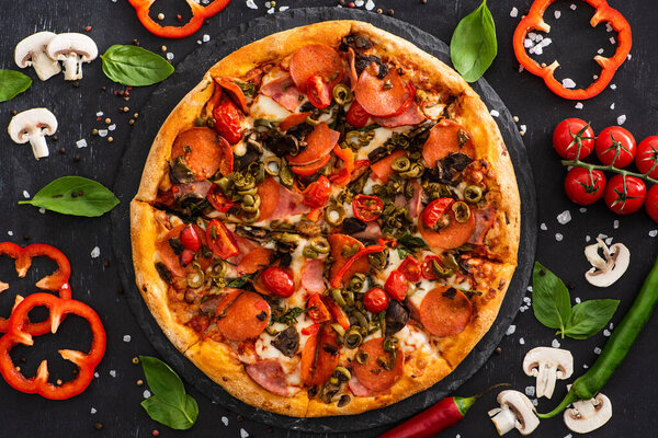 сверху вид вкусной итальянской пиццы с овощами и салями на черном фоне