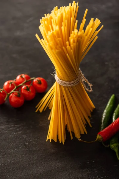 Ungekochte Italienische Spaghetti Mit Tomaten Und Chilischoten Auf Schwarzem Hintergrund — Stockfoto