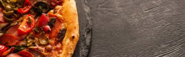 Sebzeli lezzetli İtalyan pizzası ve siyah ahşap arka planda salam, panoramik çekim