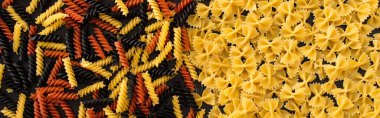 top view of raw colorful fusilli and farfalle pasta, panoramic shot clipart