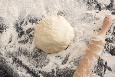 top view of rolling pin, dough on flour on black background clipart
