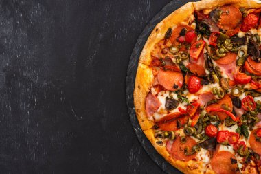Siyah ahşap arka planda salamlı lezzetli İtalyan pizzası manzarası.