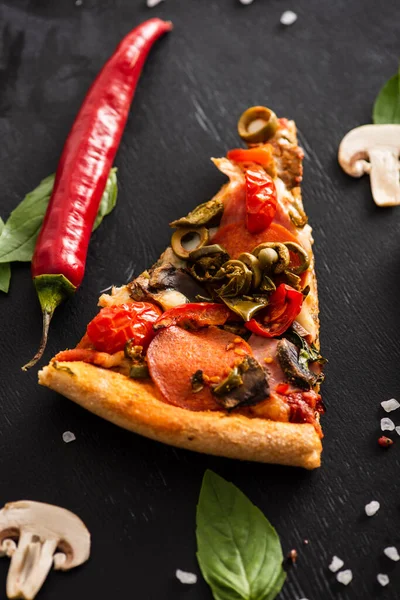 黒を基調とした野菜の近くにサラミの美味しいイタリアのピザスライスのトップビュー — ストック写真