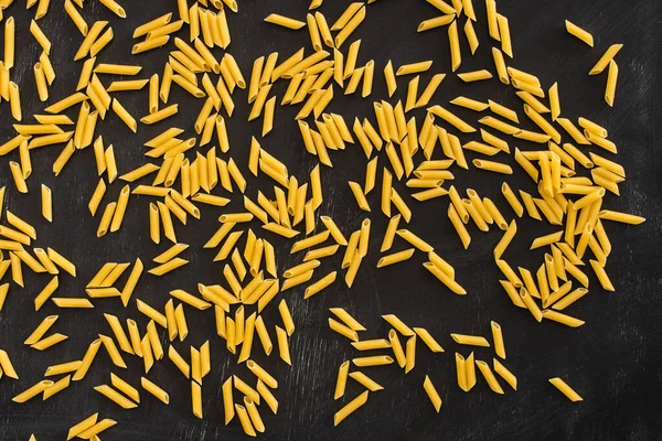 Top View Raw Penne Pasta Scattered Black Background — Stock Photo, Image