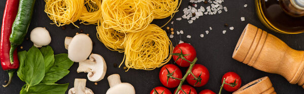 top view of raw Italian Capellini with vegetables and seasoning on black background, panoramic shot