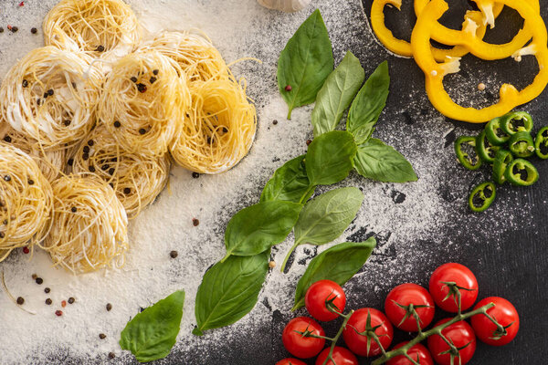 top view of raw Capellini with vegetables, spices and flour