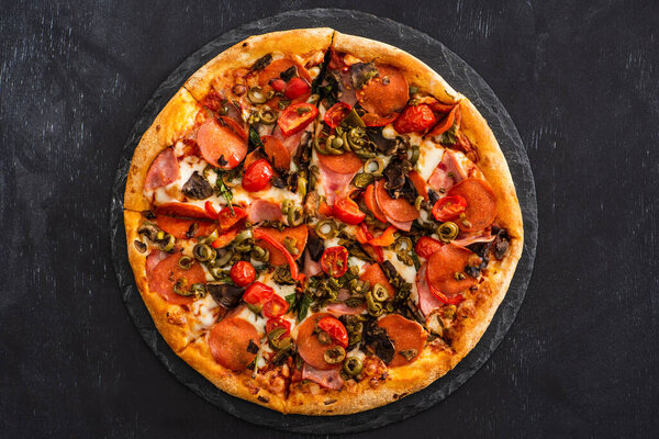 сверху вид вкусной итальянской пиццы с салями на черном деревянном фоне