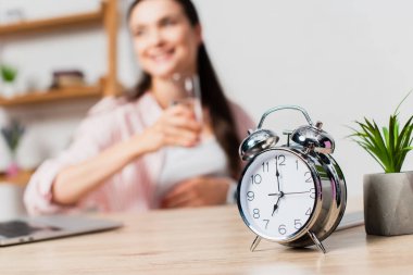 Bitki ve esmer kadının yanındaki retro alarm saatinin seçici odağı 