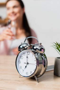 Esmer kadının yanında klasik çalar saatin seçici odak noktası 