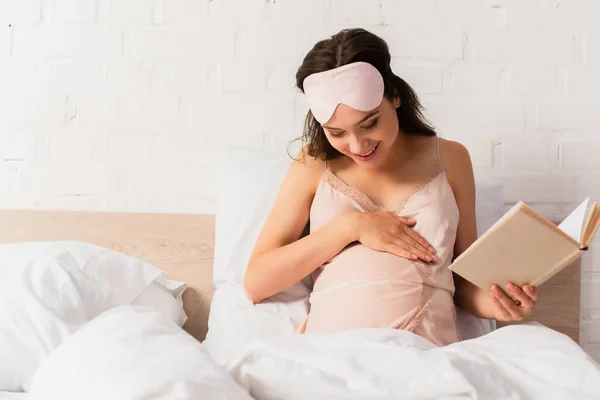 Těhotná Žena Hedvábí Noční Košile Oční Maska Držení Knihy Dotýkání — Stock fotografie