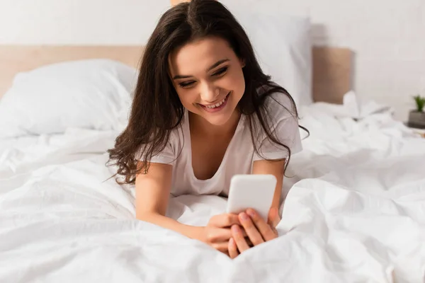 Νεαρή Γυναίκα Ξαπλωμένη Στο Κρεβάτι Και Χρησιμοποιώντας Smartphone — Φωτογραφία Αρχείου