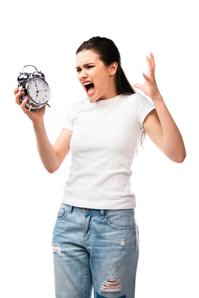 сердитая женщина в белой футболке держит ретро будильник, крича и жестикулируя изолированным на белом