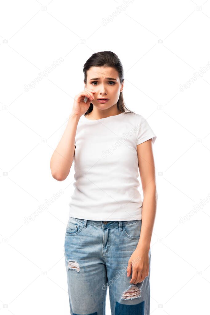 young woman in white t-shirt crying and touching face isolated on white 