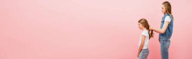 Kot elbiseli annenin yan görünüşü Pembe, web sitesi başlığında izole edilmiş kızının saçı.