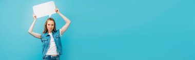 panoramik konsept kot yelek giymiş genç bir kadın kafasının üstünde mavi bir konuşma balonu tutuyor.