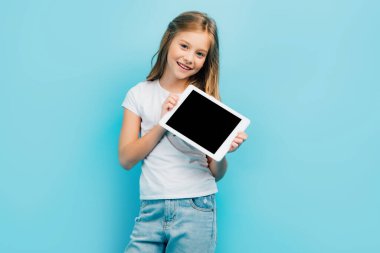 Beyaz tişörtlü ve kot pantolonlu çocuk kameraya bakarken elinde boş ekran ile dijital tablet tutuyordu.