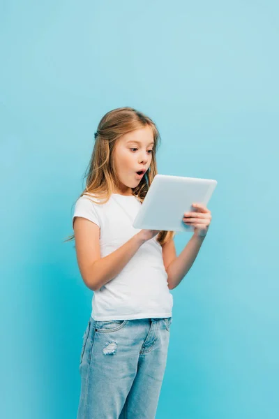 Niño Excitado Camiseta Blanca Jeans Usando Tableta Digital Aislada Azul —  Fotos de Stock