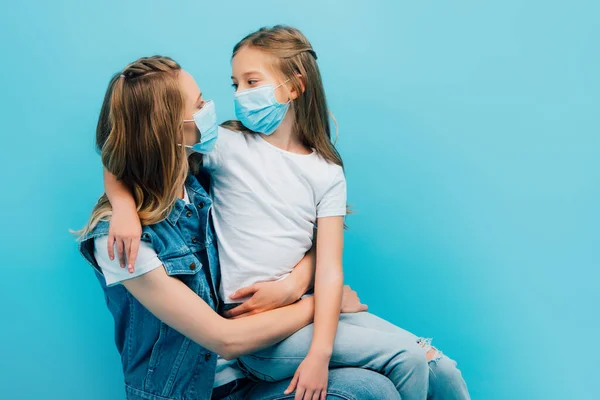 Young Woman Embracing Daughter Sitting Her Laps While Wearing Protective — Stock Photo, Image