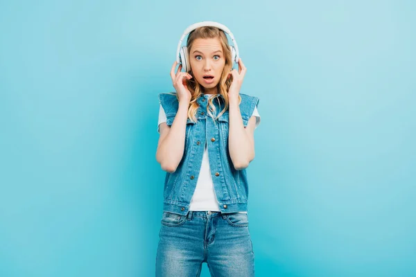 Shocked Woman Denim Clothes Touching Wireless Headphones While Looking Camera — Stock Photo, Image