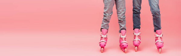 cropped view of mother and child in jeans and roller skates on pink, horizontal image