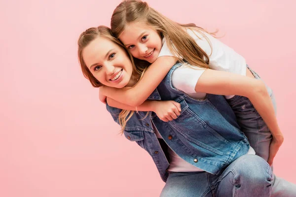 Young Mother Piggybacking Daughter While Looking Camera Isolated Pink — Stock Photo, Image