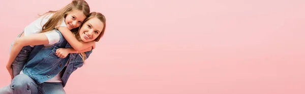 水平的なイメージの若い女性でデニムベストPiggybacking娘隔離されたピンク — ストック写真