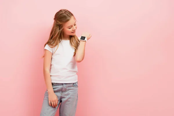 Ребенок Белой Футболке Джинсах Глядя Умные Часы Изолированы Розовый — стоковое фото