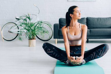 Sporcu kadın evdeki spor paspasına uzanırken gözlerini kaçırıyor. 