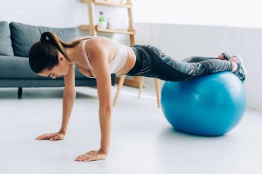 Evde fitness topuyla tahtada duran sportmen kadının seçici odağı 