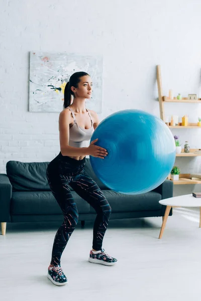 布鲁内特女运动员蹲在家里 带着健身球 — 图库照片