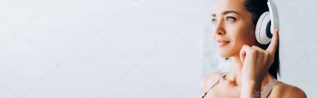 Panoramic shot of woman listening music in headphones at home 
