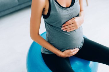 Spor giyim giymiş hamile bir kadının spor salonundaki spor salonunda karnına dokunduğu görüntüler. 