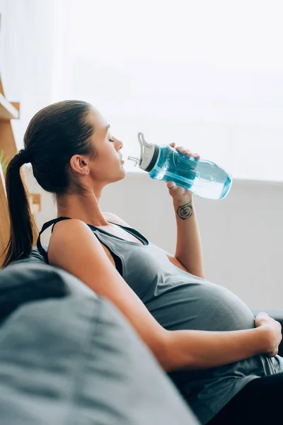 Selective Focus Pregnant Sportswoman Drinking Water While Sitting Sofa Home — Stock Photo, Image