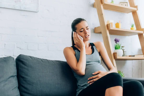 Selective Focus Pregnant Sportswoman Taking Smartphone While Feeling Pain Couch — Stock Photo, Image