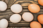 top view of fresh chicken eggs on wooden surface
