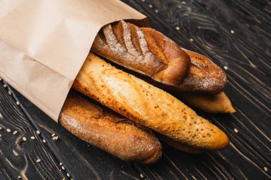 Tahta yüzeyde, kağıt torba içinde taze ekmekli ekmek.