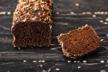 Kahverengi taze ekmeği ahşap siyah yüzeyde kesin.