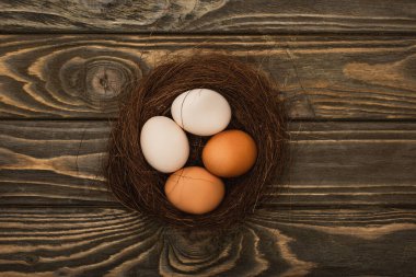 top view of fresh chicken eggs in nest on wooden surface clipart