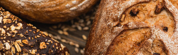 close up view of fresh baked bread loaves on wooden surface, panoramic shot