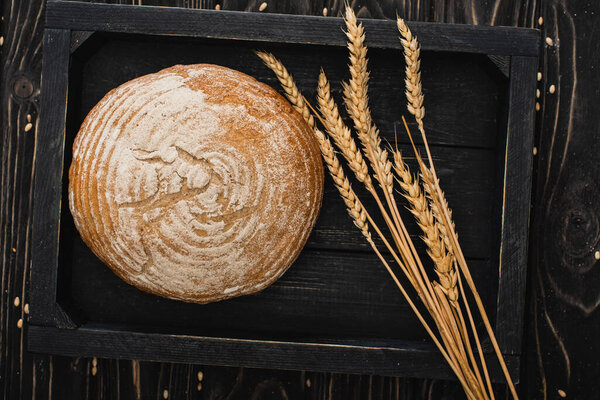 вид сверху на свежий выпеченный белый хлеб с шипами на деревянной черной доске