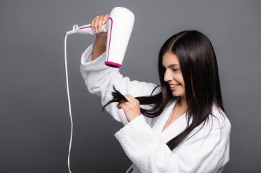 Siyah üzerine izole edilmiş saç kurutma makinesi kullanan uzun saçlı esmer kadın.