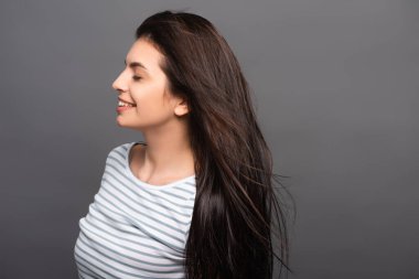 Siyah gözleri kapalı esmer kadının saçlarında esen rüzgarın yan görüntüsü.