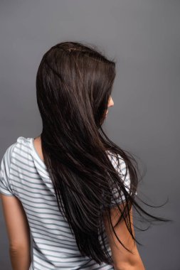 Esmer kadının saçlarında esen rüzgarın arkadan görünüşü siyah üzerine izole edilmiş.