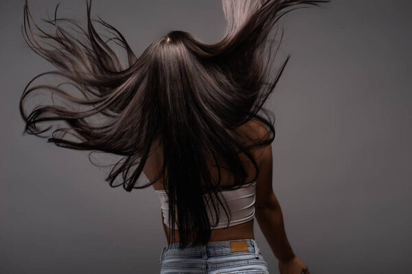 back view of brunette long haired woman isolated on black