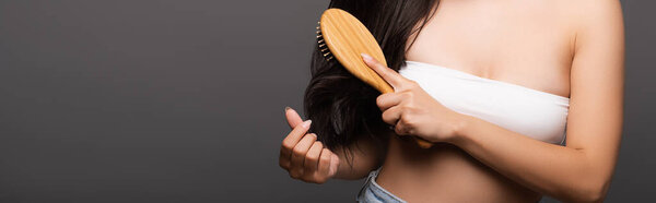 обрезанный вид брюнетки женщина расчесывая волосы изолированы на черном, панорамный снимок