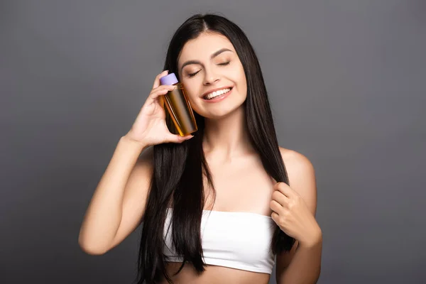 Mulher Morena Segurando Óleo Cabelo Garrafa Sorrindo Isolado Preto — Fotografia de Stock