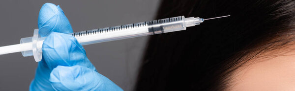 close up view of brunette woman having scalp mesotherapy isolated on black, panoramic shot