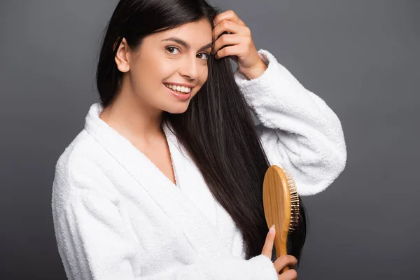 Mulher Morena Roupão Banho Escovando Cabelo Sorrindo Isolado Preto — Fotografia de Stock