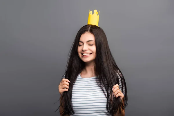 stock image brunette long haired woman in paper crown with closed eyes smiling isolated on black